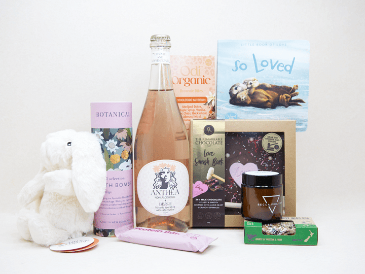 Celebrate The New Mum Gift Box featuring Anthea alcohol-free sparkling wine, Lily & George teddy bear, So Loved baby book, Becca Project candle, Botanicals bath bombs, artisan chocolate, and nourishing treats, beautifully packaged for new mums and new babies.