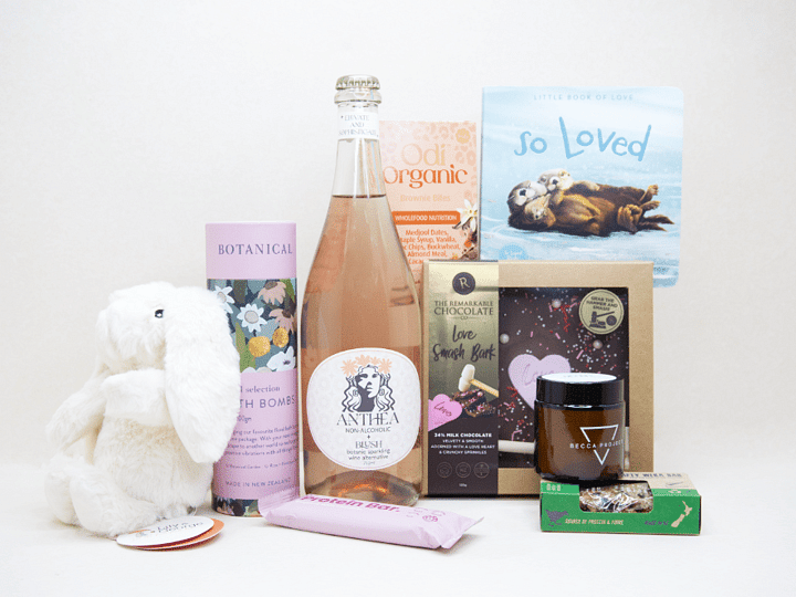 Celebrate The New Mum Gift Box featuring Anthea alcohol-free sparkling wine, Lily & George teddy bear, So Loved baby book, Becca Project candle, Botanicals bath bombs, artisan chocolate, and nourishing treats, beautifully packaged for new mums and new babies.