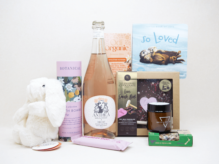 Celebrate The New Mum Gift Box featuring Anthea alcohol-free sparkling wine, Lily & George teddy bear, So Loved baby book, Becca Project candle, Botanicals bath bombs, artisan chocolate, and nourishing treats, beautifully packaged for new mums and new babies.