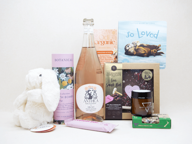 Celebrate The New Mum Gift Box featuring Anthea alcohol-free sparkling wine, Lily & George teddy bear, So Loved baby book, Becca Project candle, Botanicals bath bombs, artisan chocolate, and nourishing treats, beautifully packaged for new mums and new babies.