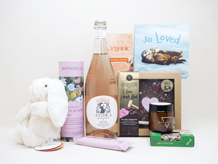 Celebrate The New Mum Gift Box featuring Anthea alcohol-free sparkling wine, Lily & George teddy bear, So Loved baby book, Becca Project candle, Botanicals bath bombs, artisan chocolate, and nourishing treats, beautifully packaged for new mums and new babies.