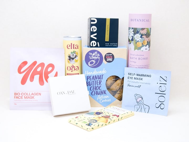 Care Package Gift Box featuring an OAN DAE wish paper kit, Soleiz eye masks, Nev&eacute; candle, floral bath bombs, Molly Woppy peanut butter cookies, YAE face mask, Bennetto chocolate, and Elta Ego self-care products, beautifully packaged to encourage relaxation and wellbeing