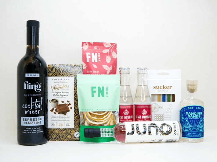 The Drinks Cart gift box featuring Juno Vodka, Dancing Sands Gin, Fling Margarita Mixer, East Imperial tonic water, FN citrus garnishes, raspberry sugar dust, Sucker glass straws, and Whittaker's coffee chocolate, beautifully packaged for cocktail lovers and entertaining.
