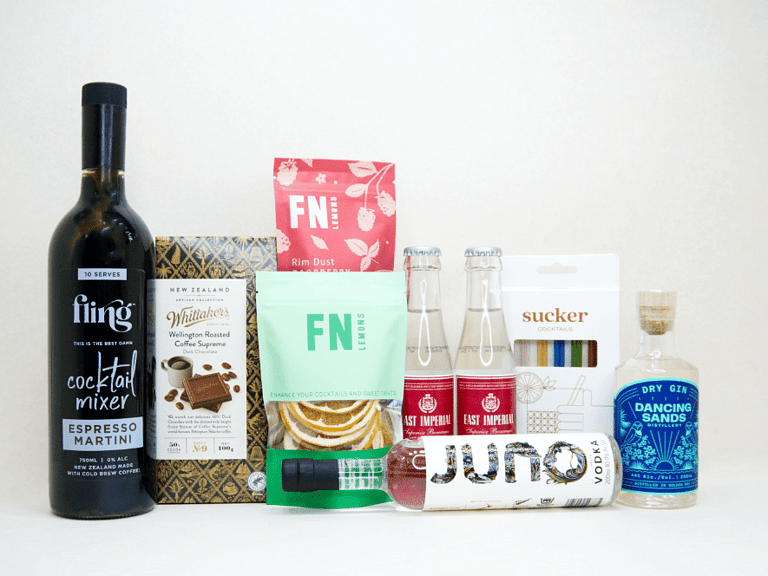 The Drinks Cart gift box featuring Juno Vodka, Dancing Sands Gin, Fling Margarita Mixer, East Imperial tonic water, FN citrus garnishes, raspberry sugar dust, Sucker glass straws, and Whittaker's coffee chocolate, beautifully packaged for cocktail lovers and entertaining.