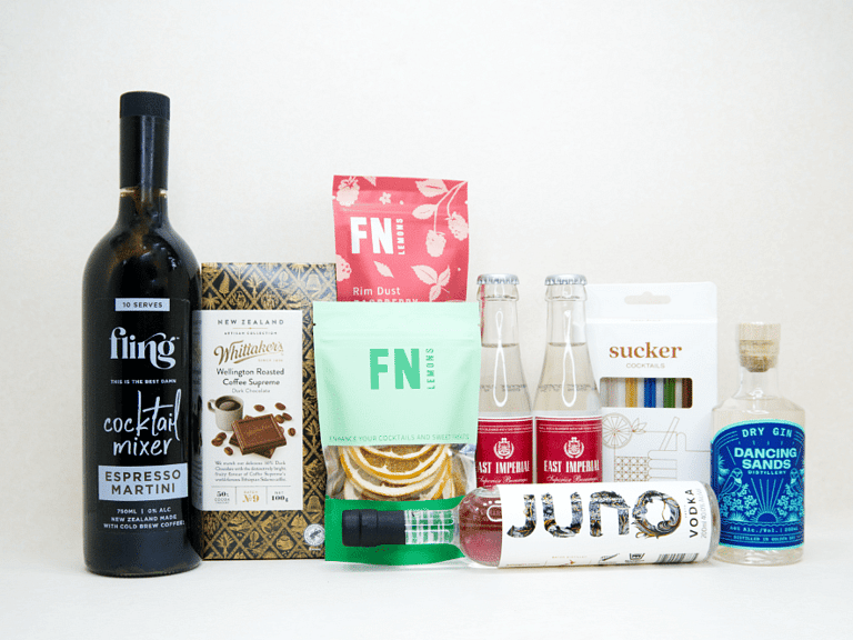 The Drinks Cart gift box featuring Juno Vodka, Dancing Sands Gin, Fling Margarita Mixer, East Imperial tonic water, FN citrus garnishes, raspberry sugar dust, Sucker glass straws, and Whittaker's coffee chocolate, beautifully packaged for cocktail lovers and entertaining.