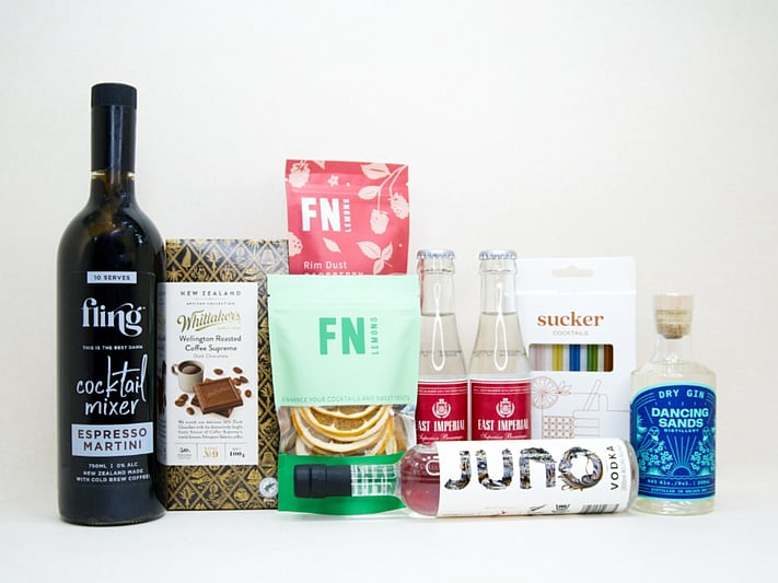 The Drinks Cart gift box featuring Juno Vodka, Dancing Sands Gin, Fling Margarita Mixer, East Imperial tonic water, FN citrus garnishes, raspberry sugar dust, Sucker glass straws, and Whittaker's coffee chocolate, beautifully packaged for cocktail lovers and entertaining.