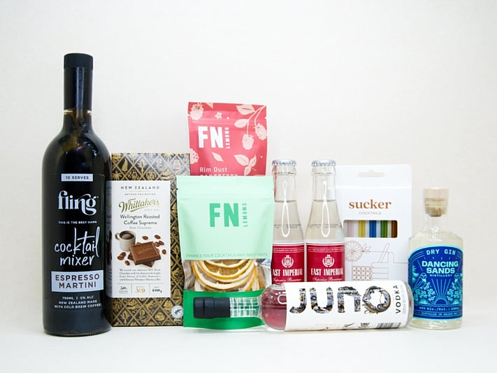 The Drinks Cart gift box featuring Juno Vodka, Dancing Sands Gin, Fling Margarita Mixer, East Imperial tonic water, FN citrus garnishes, raspberry sugar dust, Sucker glass straws, and Whittaker's coffee chocolate, beautifully packaged for cocktail lovers and entertaining.
