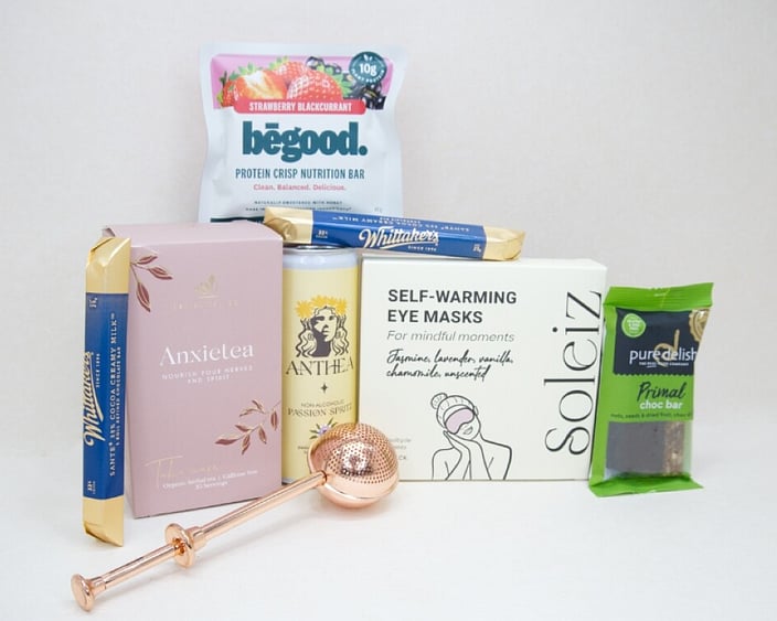 Take It Easy Gift Box featuring Better Tea Co Anxietea tea leaves, tea infuser strainer, Be Good protein bar, Whittaker's Sante bars, and Pure Delish chocolate, beautifully packaged as a calming self-care and wellness gift.
