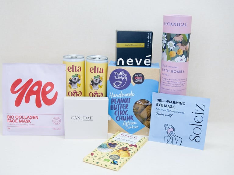 Care Package Gift Box featuring an OAN DAE wish paper kit, Soleiz eye masks, Nev&eacute; candle, floral bath bombs, Molly Woppy peanut butter cookies, YAE face mask, Bennetto chocolate, and Elta Ego self-care products, beautifully packaged to encourage relaxation and wellbeing