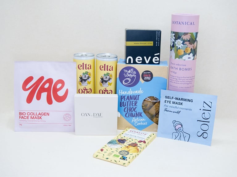 Care Package Gift Box featuring an OAN DAE wish paper kit, Soleiz eye masks, Nev&eacute; candle, floral bath bombs, Molly Woppy peanut butter cookies, YAE face mask, Bennetto chocolate, and Elta Ego self-care products, beautifully packaged to encourage relaxation and wellbeing