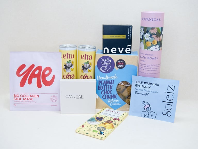 Care Package Gift Box featuring an OAN DAE wish paper kit, Soleiz eye masks, Nevé candle, floral bath bombs, Molly Woppy peanut butter cookies, YAE face mask, Bennetto chocolate, and Elta Ego self-care products, beautifully packaged to encourage relaxation and wellbeing