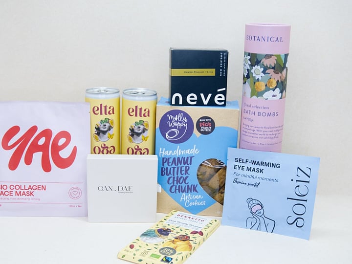 Care Package Gift Box featuring an OAN DAE wish paper kit, Soleiz eye masks, Nevé candle, floral bath bombs, Molly Woppy peanut butter cookies, YAE face mask, Bennetto chocolate, and Elta Ego self-care products, beautifully packaged to encourage relaxation and wellbeing