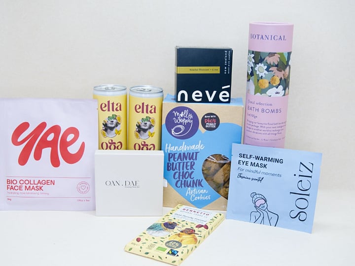 Care Package Gift Box featuring an OAN DAE wish paper kit, Soleiz eye masks, Nevé candle, floral bath bombs, Molly Woppy peanut butter cookies, YAE face mask, Bennetto chocolate, and Elta Ego self-care products, beautifully packaged to encourage relaxation and wellbeing