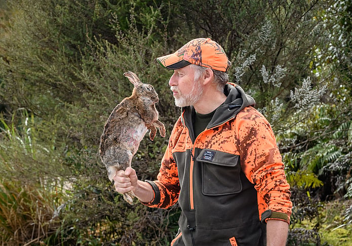 Volunteer carrying a trapped rabbit during predator control work