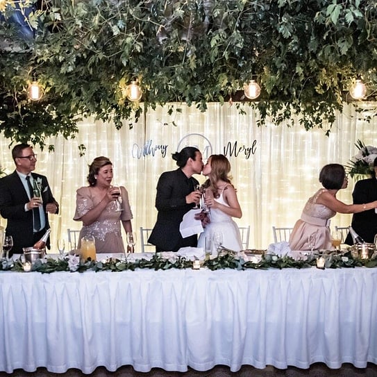 Bride & groom kissing at bridal table