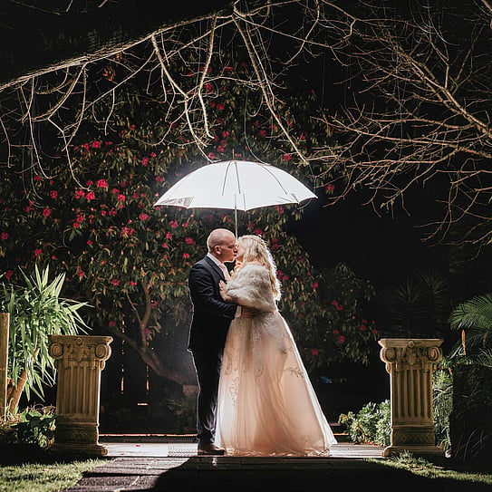 bride and groom posing with umbrella