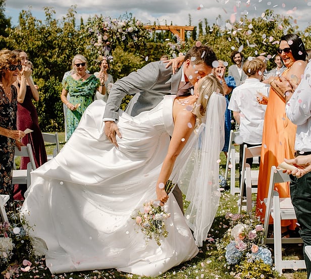 Markovina Vineyard Estate Wedding Venue Happy Couple Kissing at Cherry Blossom Ceremony Area