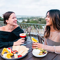 Friends enjoying drinks and food at the Library Bar located on the rooftop of the State Library of NSW