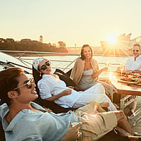 Friends enjoying drinks and snacks on board the Ghost 2 Super Yacht in Sydney Harbour during sunset.