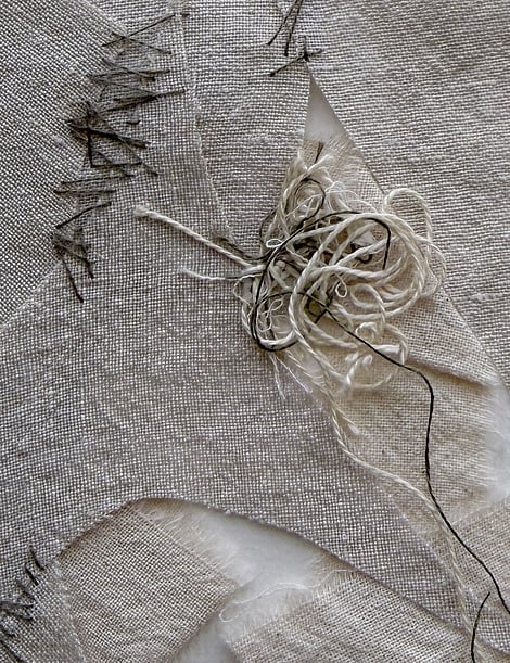 detail image of layered oatmeal and angular fawn-toned linen fragments with a messy swirl of thread remnants in the centre, hand-stitched details, visible weave texture and soft frayed edges