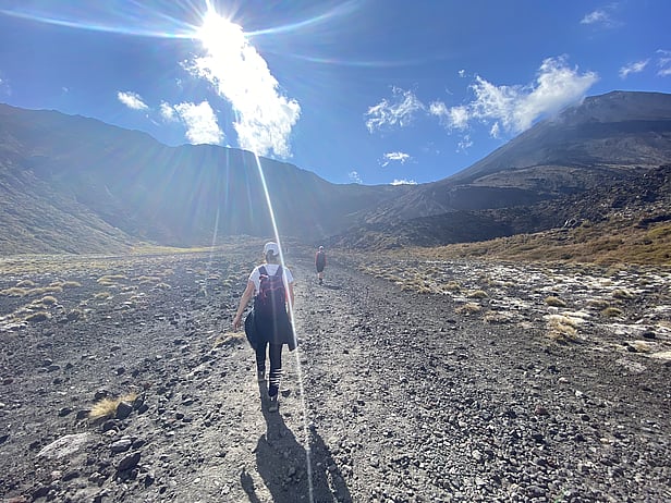 Early stages of the Tongariro Alpine Crossing under clear blue skies, crossing a vast volcanic landscape.