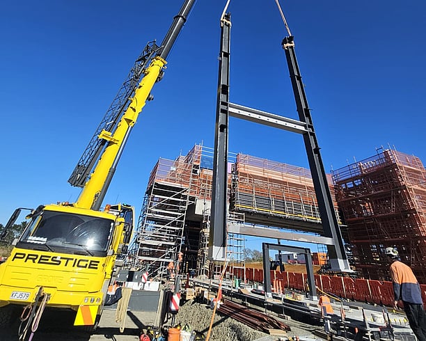 Crane lifts structural steel into place on site at Ngākōroa railway station
