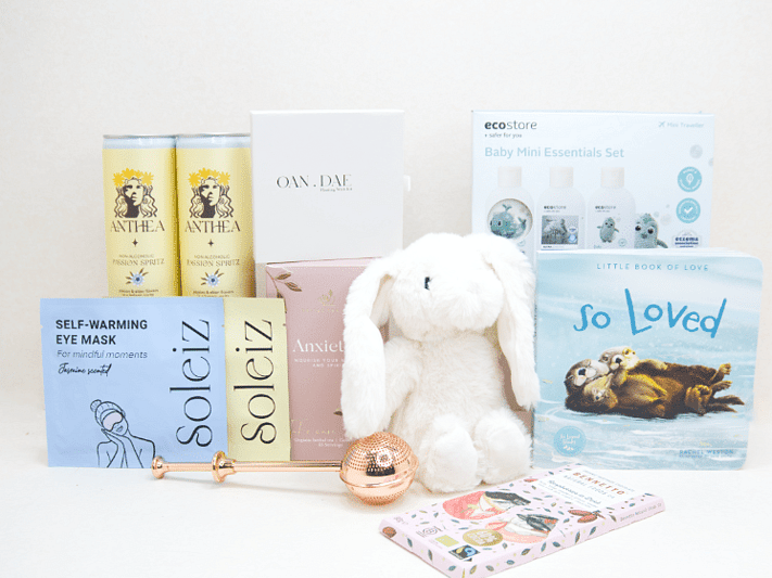 The New Chapter Gift Box featuring a bunny soft toy, baby memory book, OAN DAE Wish Kit, Soleiz eye masks, Anthea 0% Passionfruit Spritz, Anxiety Tea with tea infuser, Ecostore Mini Essentials Set, and a handwritten gift card, beautifully presented in a premium KYND gift box.