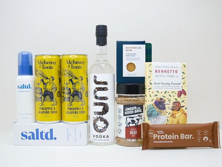The Kick Back Gift Box featuring JUNO Vodka, Saltd Magnesium spray, Botanicals body bar, Bennetto chocolate, Under the Hood BBQ spice, Nothing Naughty protein bar and Alchemy tonic mixers.
