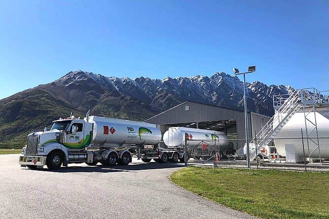 RD Petroleum aviation fuel tanker and trailer parked beside bulk storage tanks at Queenstown Airport, with the Remarkables mountain range behind.