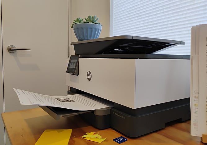 A printer-photocopier on a desk with pages ready to be picked up
