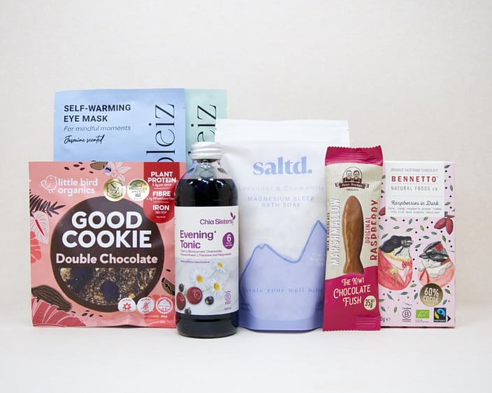 A Little Unwind Gift Box featuring Chia Sisters Evening Tonic, Saltd Magnesium Soak, Soleiz eye masks, Little Bird Organics Good Cookie, Bennetto raspberry chocolate, and Potter Brothers raspberry chocolate fish, thoughtfully curated for relaxation, rest, and self-care.
