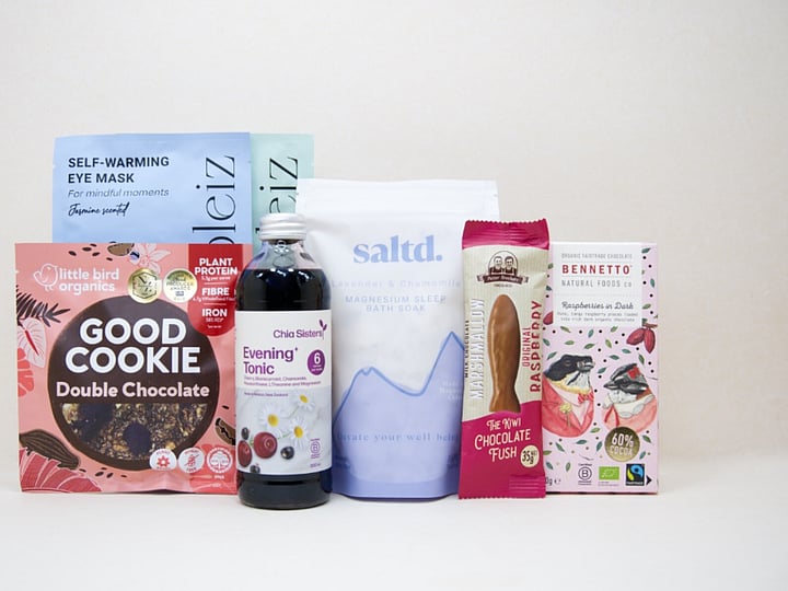 A Little Unwind Gift Box featuring Chia Sisters Evening Tonic, Saltd Magnesium Soak, Soleiz eye masks, Little Bird Organics Good Cookie, Bennetto raspberry chocolate, and Potter Brothers raspberry chocolate fish, thoughtfully curated for relaxation, rest, and self-care.