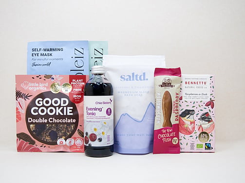 A Little Unwind Gift Box featuring Chia Sisters Evening Tonic, Saltd Magnesium Soak, Soleiz eye masks, Little Bird Organics Good Cookie, Bennetto raspberry chocolate, and Potter Brothers raspberry chocolate fish, thoughtfully curated for relaxation, rest, and self-care.