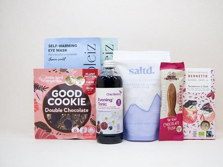 A Little Unwind Gift Box featuring Chia Sisters Evening Tonic, Saltd Magnesium Soak, Soleiz eye masks, Little Bird Organics Good Cookie, Bennetto raspberry chocolate, and Potter Brothers raspberry chocolate fish, thoughtfully curated for relaxation, rest, and self-care.