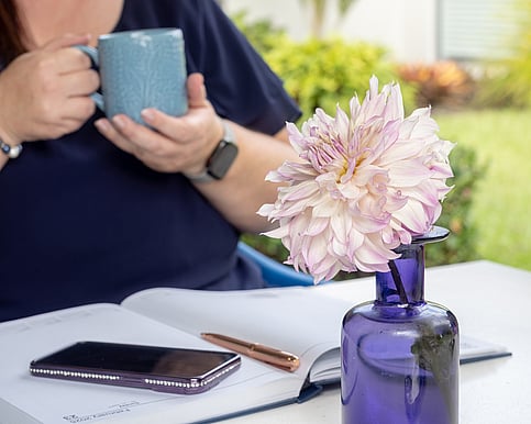 Image of a coffee mug and a flower in a jar with the text "traffic goes somewhere"