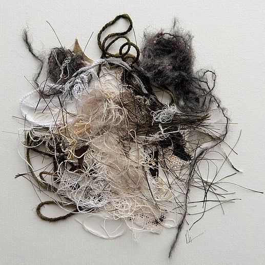 full image of a layered textile work of repurposed yarn, threads and fabric remnants in neutral tones, showing a dense, messy cluster of tangled loops, varied textures, frayed fibres and handwritten signature