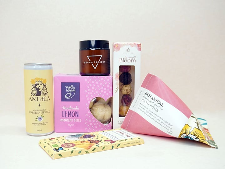 Just Lovely Gift Box featuring Better Tea Co blooming tea balls, Anthea cocktail, Becca Project Stella candle, Botanicals bath bomb, Molly Woppy Lemon Moments, and Bennetto salted caramel chocolate, thoughtfully curated to brighten someone's day and encourage relaxation.