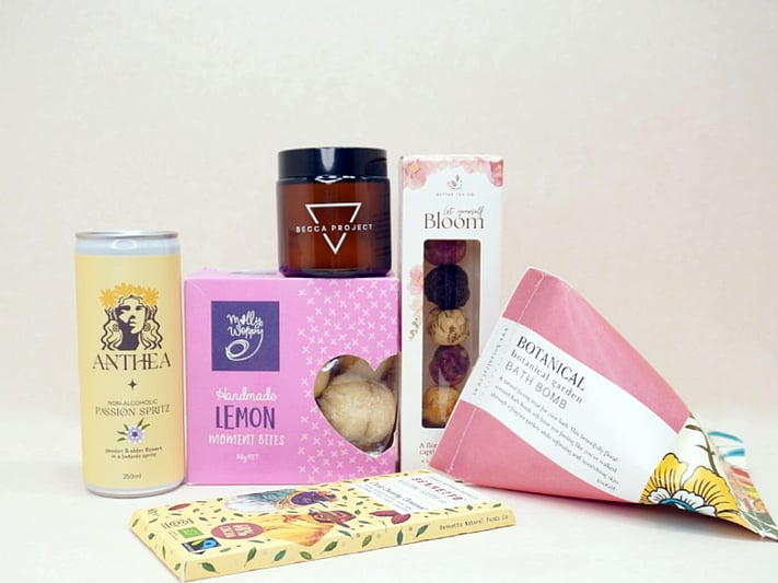 Just Lovely Gift Box featuring Better Tea Co blooming tea balls, Anthea cocktail, Becca Project Stella candle, Botanicals bath bomb, Molly Woppy Lemon Moments, and Bennetto salted caramel chocolate, thoughtfully curated to brighten someone's day and encourage relaxation.
