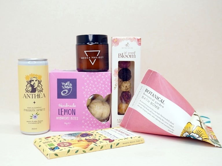 Just Lovely Gift Box featuring Better Tea Co blooming tea balls, Anthea cocktail, Becca Project Stella candle, Botanicals bath bomb, Molly Woppy Lemon Moments, and Bennetto salted caramel chocolate, thoughtfully curated to brighten someone's day and encourage relaxation.