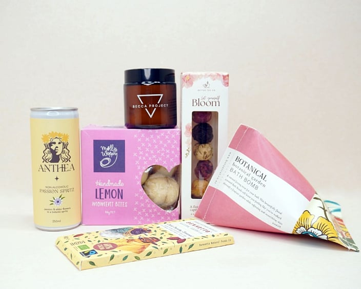 Just Lovely Gift Box featuring Better Tea Co blooming tea balls, Anthea cocktail, Becca Project Stella candle, Botanicals bath bomb, Molly Woppy Lemon Moments, and Bennetto salted caramel chocolate, thoughtfully curated to brighten someone's day and encourage relaxation.