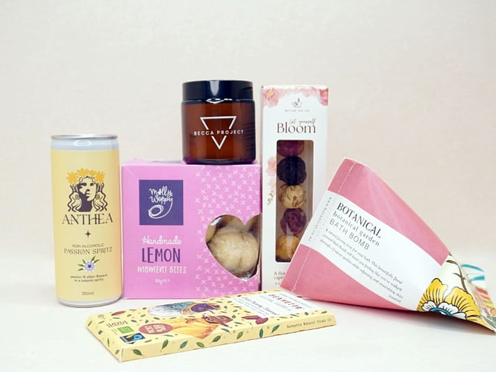 Just Lovely Gift Box featuring Better Tea Co blooming tea balls, Anthea cocktail, Becca Project Stella candle, Botanicals bath bomb, Molly Woppy Lemon Moments, and Bennetto salted caramel chocolate, thoughtfully curated to brighten someone's day and encourage relaxation.
