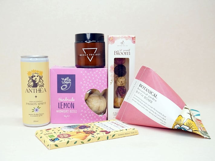 Just Lovely Gift Box featuring Better Tea Co blooming tea balls, Anthea cocktail, Becca Project Stella candle, Botanicals bath bomb, Molly Woppy Lemon Moments, and Bennetto salted caramel chocolate, thoughtfully curated to brighten someone's day and encourage relaxation.