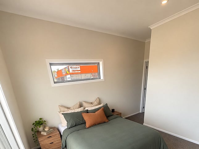Main bedroom with green bedding and a high window