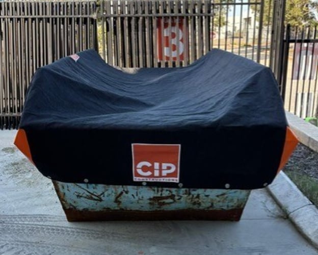 Custom skip bin cover fitted over a construction site skip bin
