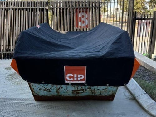 Custom skip bin cover fitted over a construction site skip bin