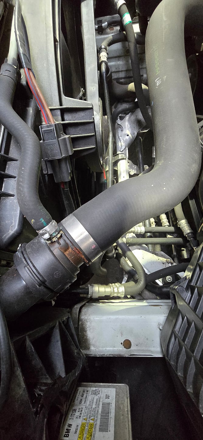 BMW engine bay showing deterioration around a coolant hose connection