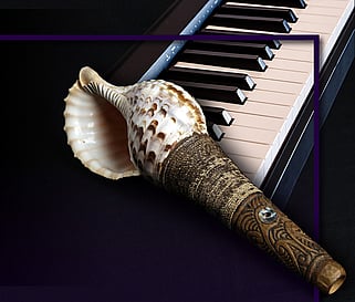 Black background wit piano keyboard in top right half of image and a Maori percussion instrument with shell and carved flute in the centre.