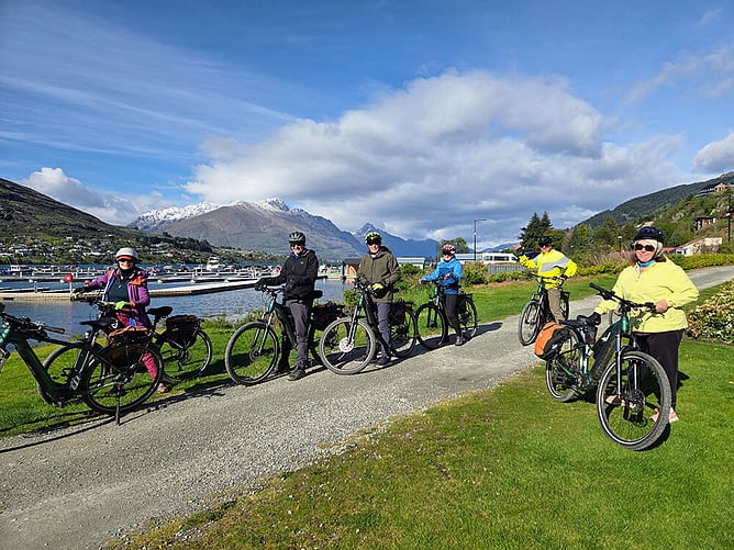 A group of riders with e-bikes beside Lake Wakatipu in Queenstown, spring cycling on New Zealand's South Island