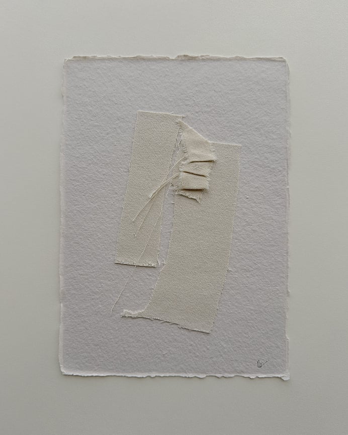 full image of a layered collage on handmade sand-toned, deckled-edged cotton rag paper showing three repurposed oat-toned cotton fragments, with one small fragment hand-stitched into gentle folds and secured on top, visible weave texture, soft frayed edges and downward hanging threads, with handwritten signature in lower right corner