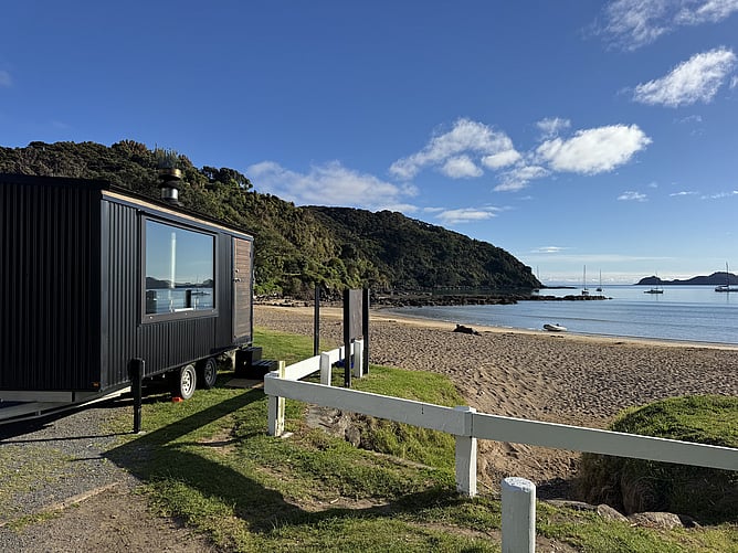Wood-fired mobile beach sauna trailer on the sand at Long Beach Oneroa Bay in Russell